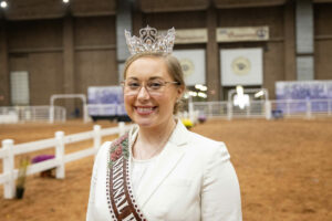 A woman wearing a tiara at a Herefords cattle sale in an arena.