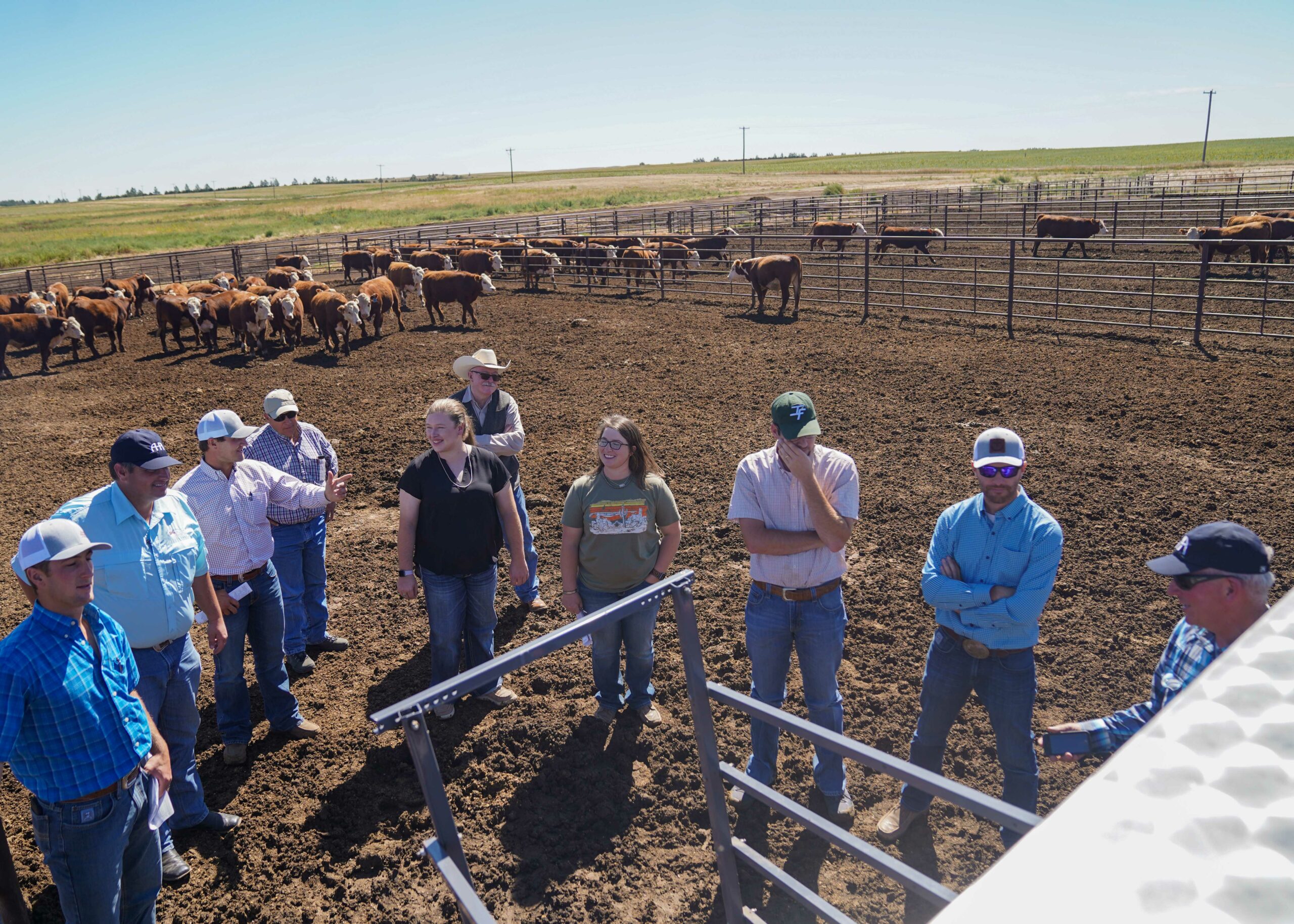 A group of Seedstock Academy members standing in front of a Hereford cattle pen.